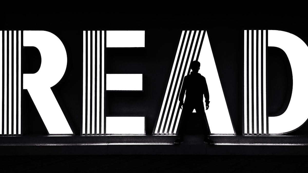 A black and white photo of a man standing in front of the word read