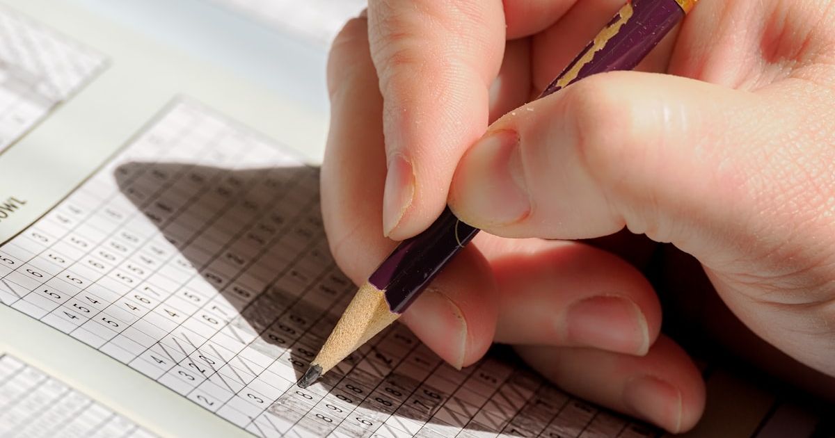 A person holding a pencil and writing on a piece of paper