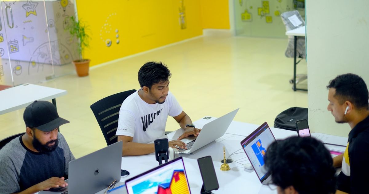 man in white polo shirt sitting on chair using macbook